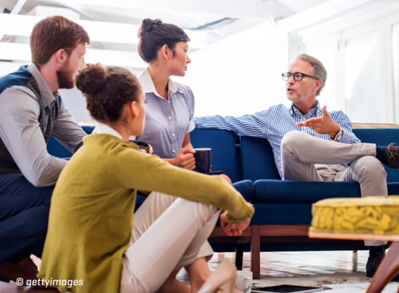 Quatre personnes sur et autour de la chaise discutant de quelque chose.